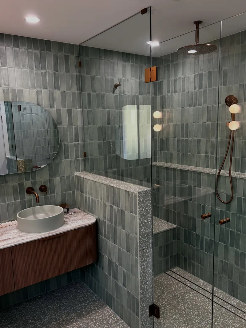 Frameless shower screen with brass fittings in a tiled bathroom